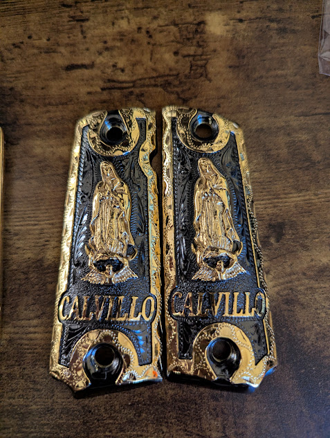 Custom gold and black Colt 1911 pistol grips with CALVILLO engraving and religious design