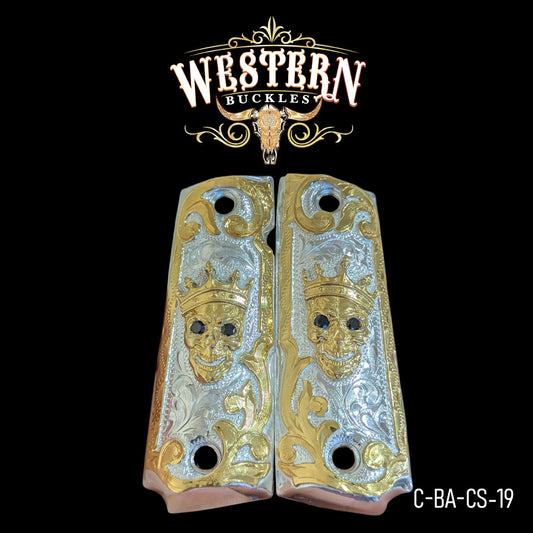 Gold and silver engraved 1911 pistol grips with crowned skull design on black background.