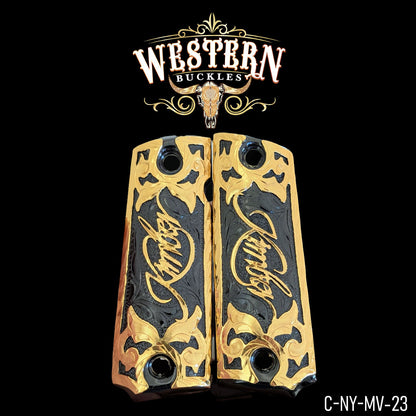 Gold and black custom 1911 pistol grips with ornate Western design and engraved script.