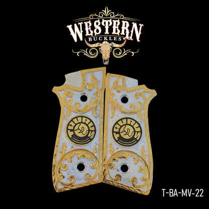 Gold and silver Taurus pistol grips with engraved scrollwork design on black background