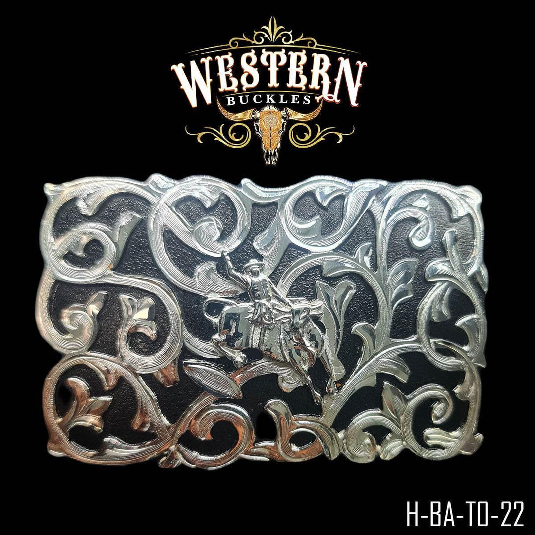 Silver western belt buckle with ornate scroll design and cowboy riding horse motif